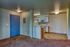 Inviting entryway with vibrant blue door leading to a cozy kitchen and warm carpeted area, perfect for comfort.