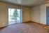 Bright and inviting apartment living room with plush carpeting, large sliding glass doors opening to a scenic balcony view.