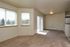 Bright and inviting living space with plush carpet, large windows offering scenic views, and an adjoining balcony area.