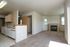 Bright living space with cozy carpeted flooring, fireplace, and modern kitchen featuring sleek cabinetry and built-in appliances.