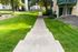 Inviting walkway leading to charming apartment entrance surrounded by lush greenery and mature trees.