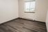 Bright corner room with elegant wooden flooring and a sunlit window, offering a cozy and inviting space.