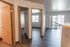 Bright apartment interior with wood floors, open closet, and sliding doors leading to a balcony with scenic views.