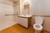 Modern bathroom with sleek wooden flooring, accessible shower, and stylish vanity in a welcoming and functional design.