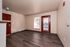 Bright apartment entrance with stylish dark wood flooring, large window, and modern red door providing a warm and inviting ambiance.