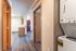 Bright and welcoming apartment hallway with sleek wood flooring, in-unit washer and dryer, and a cozy glimpse into a modern kitchen area.