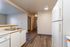 Modern apartment kitchen with sleek white cabinetry, integrated dishwasher, and elegant wood flooring.