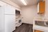 Modern kitchen with sleek white appliances, stylish wood cabinetry, and elegant grey flooring.