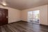 Bright living room with elegant hardwood flooring, sliding glass door leading to balcony, and welcoming entrance door.