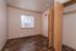 Bright and inviting bedroom with warm wood flooring, an open closet, and ample natural light streaming through a window with blinds.