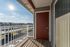 Welcoming balcony view with vibrant sunlight, overlooking modern apartment complex and clear blue skies.