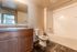 Inviting bathroom with elegant wooden cabinetry, sleek granite countertop, and a modern bathtub for a relaxing experience.