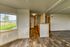 Elegant open-plan apartment showcasing a spacious living area with wooden flooring, abundant natural light, and scenic countryside views through a large window.