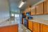 Modern kitchen with elegant wooden cabinetry, marble countertops, and a sleek black appliance set. Sunlit space with stylish flooring and ample room for culinary creativity.