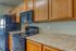 Modern kitchen with sleek black appliances, stylish wooden cabinets, and elegant granite countertops, perfect for culinary adventures.