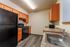 Well appointed apartment kitchen featuring all black appliances - refrigerator, oven & range with vent hood, microwave and dishwasher as well as stainless steel sink, all wood cabinets and granite-style laminate countertops