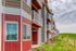 Charming modern apartment complex with vibrant red siding and private balconies overlooking lush green surroundings.