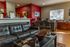 Inviting office space with a stylish gray leather sofa, vibrant red accent wall, and ample natural light.
