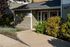 Charming apartment exterior with a lush garden, showcasing a pet-friendly and laundry-equipped community space enhanced by natural light.