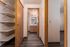Inviting apartment hallway with contemporary wooden accents leading to a well-lit bathroom, featuring a sleek built-in closet with ample shelving.