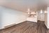 Modern open-concept living area with sleek wood flooring and a cozy kitchen featuring wooden cabinetry and appliances.