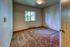 Cozy bedroom with soft carpet flooring and a window offering lush green views, perfect for relaxation.