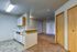 Modern apartment interior showcasing an open kitchen with sleek cabinets, adjacent to a cozy carpeted living area with natural light.