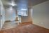Modern open-plan apartment featuring a cozy carpeted living space adjacent to a sleek kitchen with wood cabinets and bright lighting.