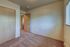 Cozy sunlit room with plush carpet flooring and a large window, featuring wooden doors and ample wall space.