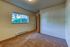 Bright bedroom with plush carpeting and large window overlooking greenery, offering ample natural light and a cozy atmosphere.