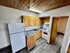 Charming apartment kitchen featuring sleek granite countertops, classic wooden cabinets, and modern appliances with a cozy wooden ceiling.