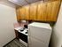 Cozy kitchen with warm wooden cabinets, sleek white appliances, and charming pink tile backsplash in a compact yet functional design.