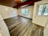 Bright and spacious room with elegant wood panel ceiling and modern vinyl flooring, large windows offering abundant natural light.