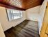 Bright and spacious apartment room with a large window offering stunning outside views, featuring elegant wooden floors and a stylish wooden ceiling.