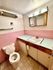 Charming bathroom with retro pink tiles, modern vanity, and ample lighting, offering a cozy and stylish ambiance.