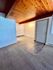Charming room with warm wooden ceiling, carpeted floor transitioning to stylish laminate, and natural light setting a cozy ambiance.