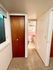 Cozy hallway leading to a quaint bathroom with vintage pink tiles and a wooden closet, perfect for inviting warmth into your home.