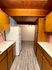 Charming kitchen with warm wood cabinetry, sleek white appliances, and elegant wood-paneled ceiling for a cozy, inviting atmosphere.