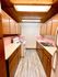 Charming galley kitchen featuring warm wood cabinetry, pink tile accents, and modern appliances under a stylish wood-paneled ceiling.