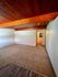 Charming living area with warm wood-paneled ceiling and inviting carpet flooring, perfect for a cozy home setting.