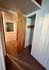 Cozy apartment hallway featuring a wooden door, built-in closet space, and carpeted floors, illuminated by soft natural light.