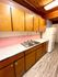 Charming kitchen with warm wooden cabinets, sleek countertop, and vintage pink tile backsplash.