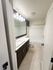 Modern bathroom featuring sleek dark cabinetry, elegant tile flooring, and a spacious bathtub with contemporary lighting.
