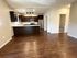 Chic open-concept kitchen and living area with modern dark wood cabinets and sleek hardwood floors, offering a warm and inviting ambiance.