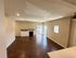 Spacious living area with elegant hardwood floors, ample natural light, and a cozy corner fireplace, perfect for entertaining.