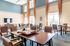 Elegant community game room with high ceilings, abundant natural light, stylish seating, and a large wall-mounted TV, perfect for social gatherings.