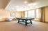 Inviting game room featuring a modern pool table, comfortable seating, and large windows allowing natural light.