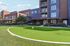 Contemporary apartment building with a lush green putting area, blending modern architecture and leisure amenities.