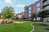 Charming modern apartment complex with well-maintained landscaping and a relaxing putting green under a clear blue sky.