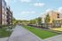 Modern apartment complex with spacious outdoor walkway and lush green spaces, ideal for relaxation and leisure.